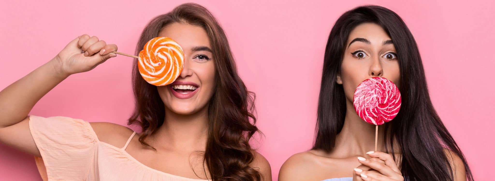 Two attractive fancy friends holding colorful lollipops Two attractive fancy friends holding colorful lollipops