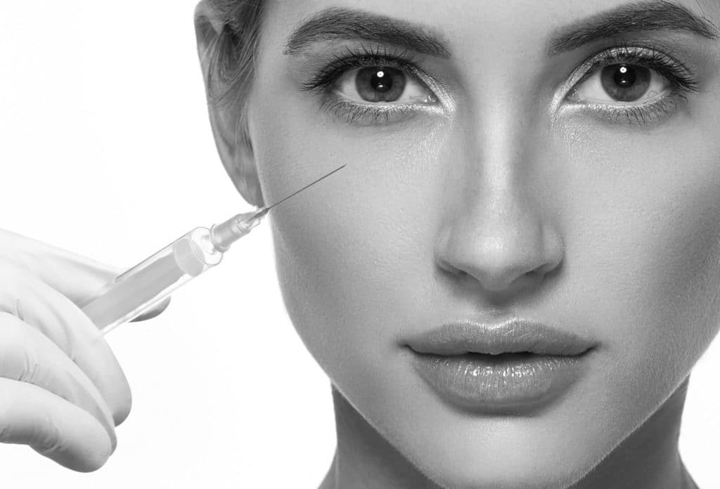 A woman with syringe near her face who could experience filler fatigue
