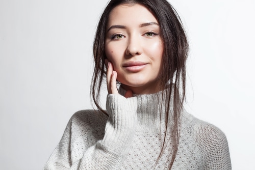 Mujer muy sonriente con piel limpia en suéter blanco esponjoso