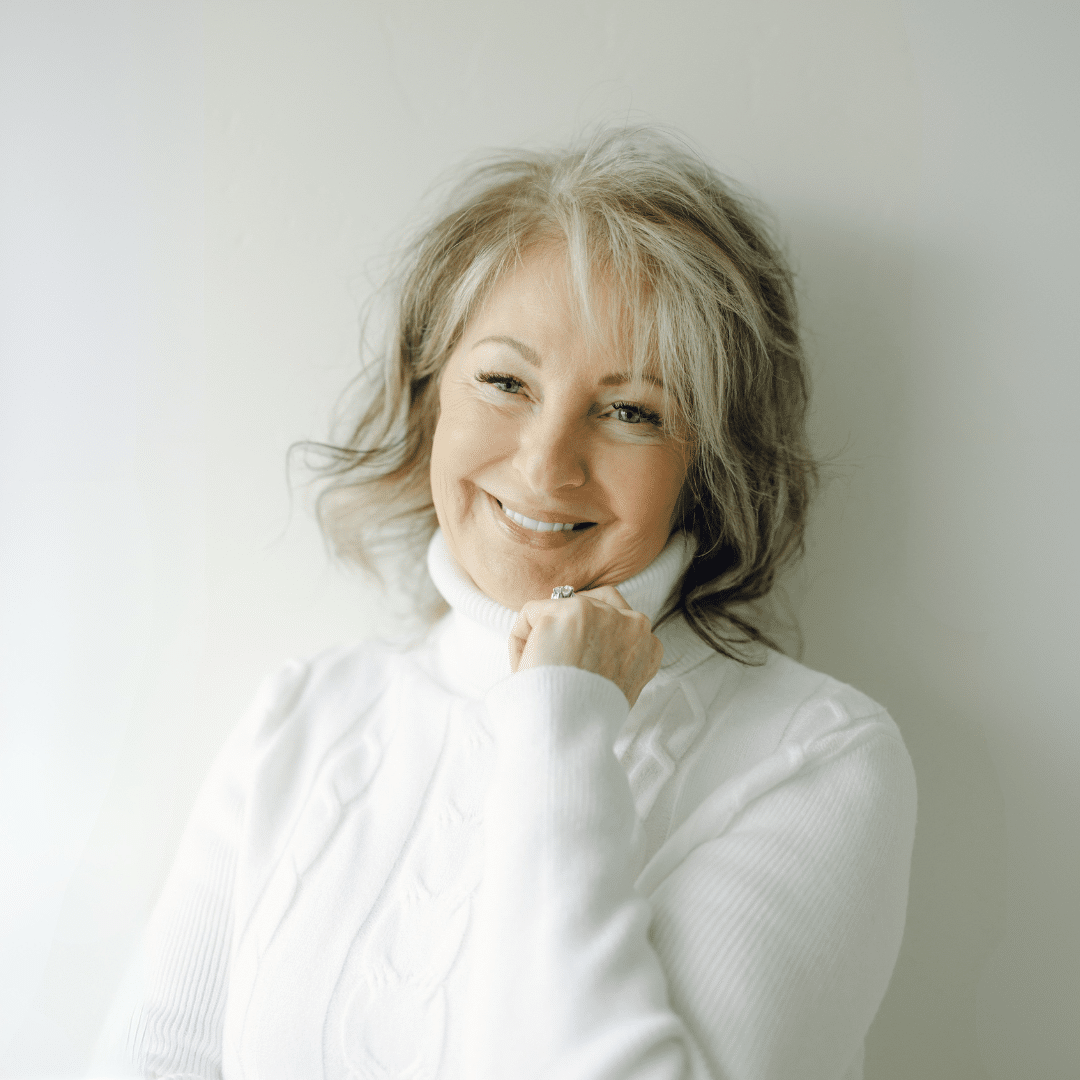 Utah Facial Plastics patient smiling in a white sweater, showcasing a refreshed, natural-looking appearance after facial rejuvenation.