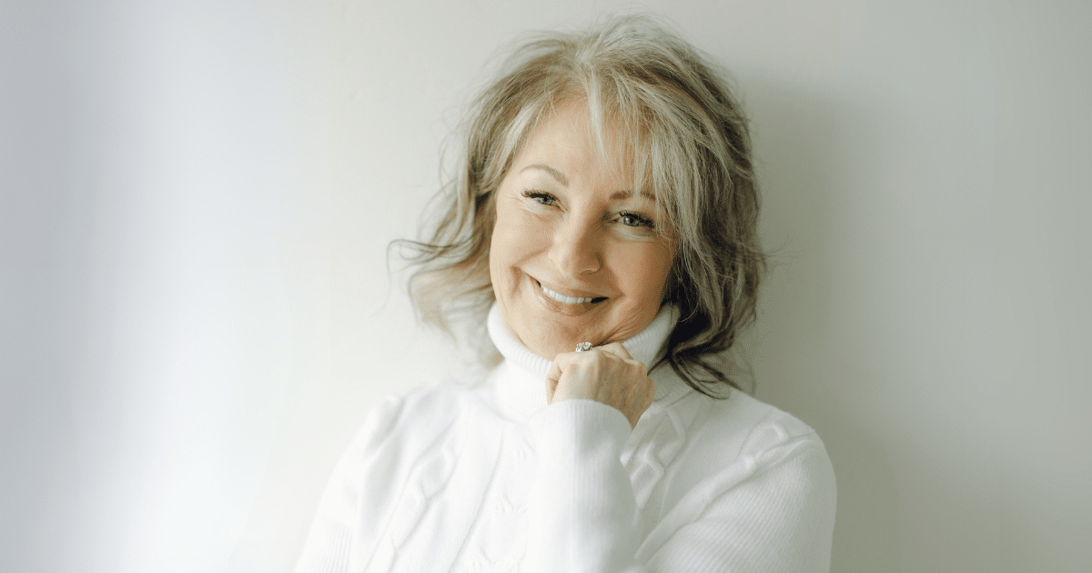 Utah Facial Plastics patient smiling in a white sweater after facial rejuvenation.